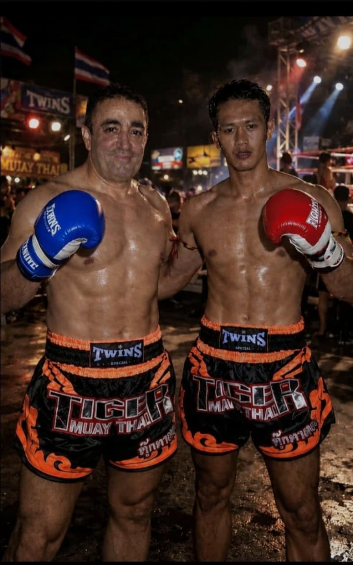 Fernando González Cruz con guantes y pantalón de Tiger Muay Thai, junto a otro luchador, tras un combate en Phuket